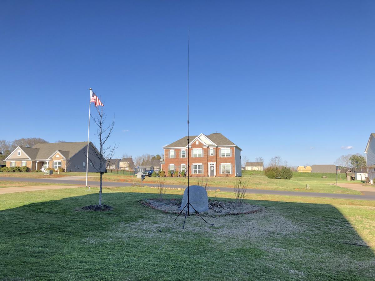 A vertical antenna on a tripod in the front yard
